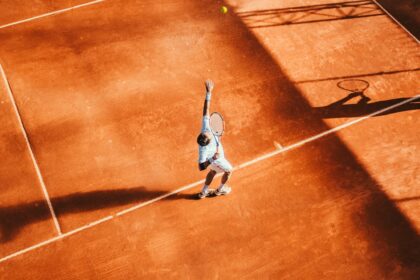 Man playing tennis on a court, representative image