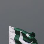 The national flag of Pakistan flying against a stormy sky