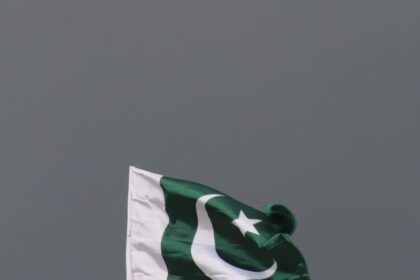 The national flag of Pakistan flying against a stormy sky