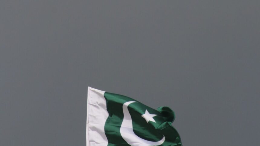 The national flag of Pakistan flying against a stormy sky