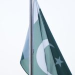 Pakistani national flag flying against a green backdrop, illustrative image