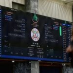 A stock broker watches share prices on a digital board at the Pakistan Stock Exchange in Karachi