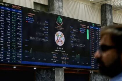 A stock broker watches share prices on a digital board at the Pakistan Stock Exchange in Karachi